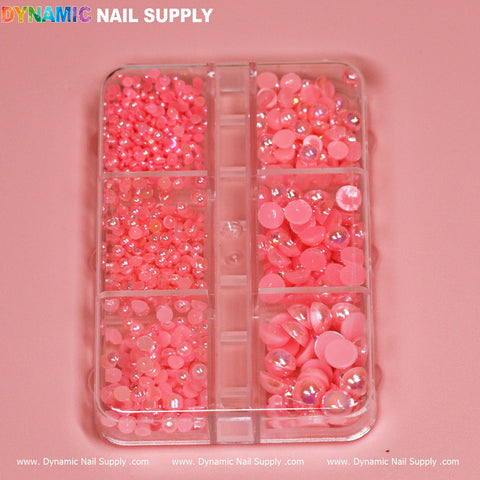 A clear plastic container with multiple compartments is filled with pink pearl and ball beads for nail design, set against a smooth pink background. At the top, "Dynamic Nail Supply" is written in colorful letters. Ideal for any nail artist!