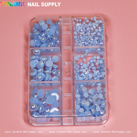 The Icy Blue Pearl / Ball Bead for Nails Design, by Dynamic Nail Supply, comes in a clear plastic organizer featuring eight compartments filled with light blue nail art rhinestones and shimmering pearls. Set against a soft pink background, the colorful Dynamic Nail Supply logo in the top left corner makes it an ideal choice for any nail designer looking to add a creative touch.