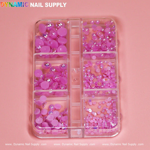 A transparent container with eleven compartments is filled with assorted sizes and shades of light purple pearl/ball beads, ideal for any nail designer. The background features a soft pink surface. The brand name Dynamic Nail Supply is printed in colorful text at the top left corner and in white text at the bottom of the image.