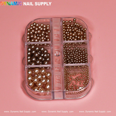 A clear plastic case featuring six compartments filled with small metallic Bronze Ball Beads in various shades of gold and bronze is displayed against a pink background. Designed for nails, the brand name "Dynamic Nail Supply" is written in colorful letters at the top left, with their website URL repeated along the bottom edge.