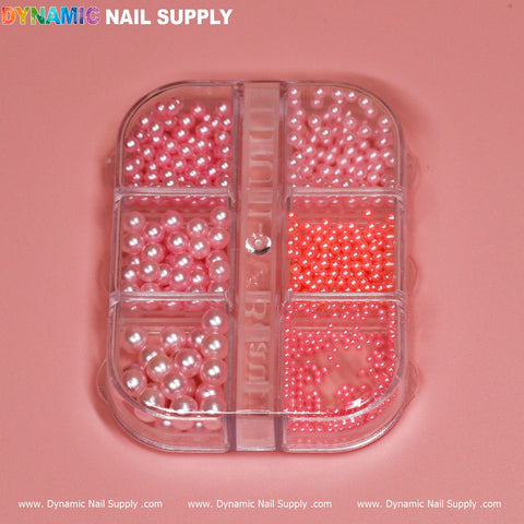 The Light Pink Pearl / Bead for Nails Design from Dynamic Nail Supply includes a transparent plastic container with a pink base and six compartments filled with nail art pearls in different shades and sizes. These glossy pearls, ranging from light pink to coral, offer an exquisite addition to any manicure, ideal for the aspiring nail designer.