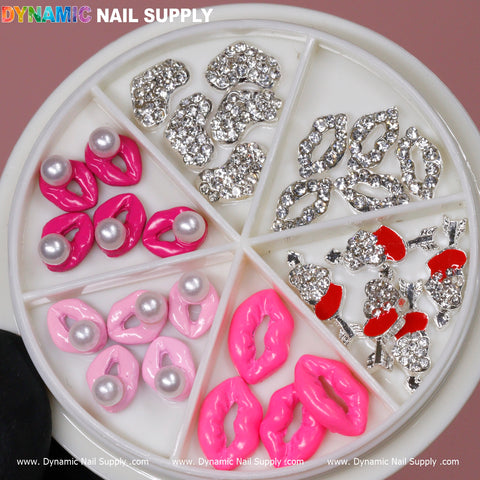 Dynamic Nail Supply offers a round container with six compartments filled with an enchanting collection of nail charms. In the top left and center, you'll find silver lip charms, while the top right holds charming silver bow ties. The bottom left compartment contains pink lips embellished with pearls, the bottom center features 3D Lips Nail Charms from their 30 pcs set, and the bottom right is home to silver bows accented with red enamel on a light pink background.