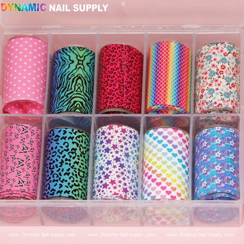A transparent plastic box features 12 rolls of Dynamic Nail Supply's Nail Art Design Foils - Colorful, showcasing a variety of patterns like pink dots, green zebra, pink leopard, rainbow scales, and more. Perfect for creating vibrant nail art, these design foils add flair to any style. The brand name "DYNAMIC NAIL SUPPLY" is prominently printed on the box.