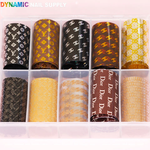 The Nail Art Design Foils - Luxury Style, from Dynamic Nail Supply, come in a clear plastic organizer that accommodates ten rolls. Each roll highlights luxury style-inspired patterns with logos in black, gold, white, and orange on reflective backgrounds. The top left corner of the organizer is adorned with the Dynamic Nail Supply name in vibrant text.