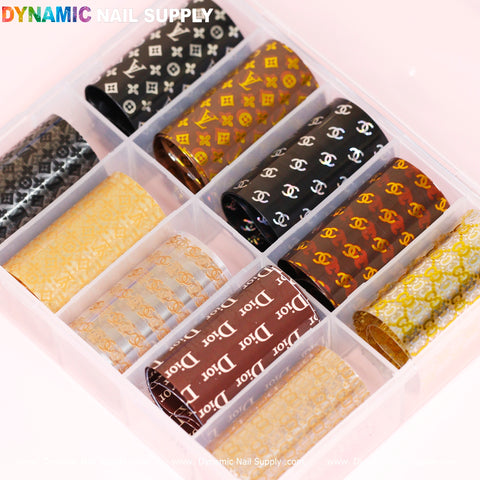 Dynamic Nail Supply's Nail Art Design Foils - Luxury Style features a plastic organizer that accommodates nine rolls of foils, each displaying elegant repeating motifs with the iconic brand logo patterns. Available in a palette of black, gold, red, brown, and silver, these designs present a neat and vibrant arrangement.