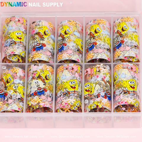 A clear plastic organizer with ten compartments contains the Nail Art Design Foils - Cartoon Style, produced by Dynamic Nail Supply. These foils display vibrant nail art designs featuring colorful cartoon characters, such as a yellow sponge and a pink starfish, amidst flowers and bubbles. The top of the organizer is branded with the name Dynamic Nail Supply.