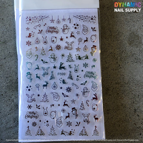 A sticker sheet on a gray surface features an array of vibrant Christmas-themed nail art designs, such as snowflakes, Santa faces, Christmas trees, stars, reindeer, and "Merry Christmas" text. This festive collection is labeled F599 and includes a Dynamic Nail Supply watermark at the top, making it ideal for holiday nail designs.