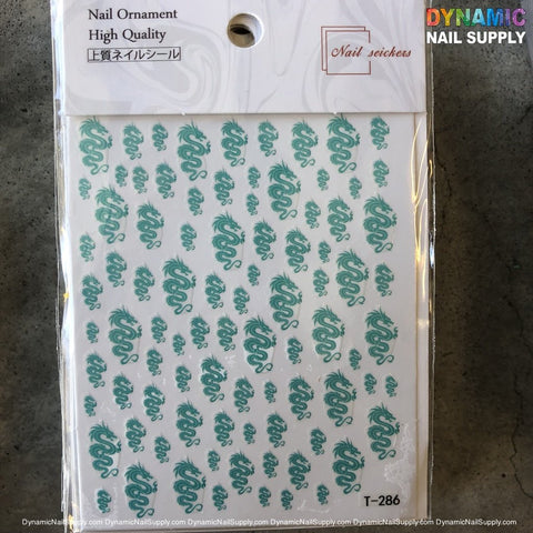 A nail ornament sheet showcasing turquoise dragon stickers is arranged in neat rows on a white background. The packaging header features the brand name Dynamic Nail Supply along with a "High Quality" text. In the bottom right corner, the code T286 is displayed. Placed on a gray surface, this sheet is ideal for intricate nail art enthusiasts.