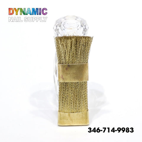 A copper wire brush designed for cleaning nail drill bits stands elegantly against a white background. Its transparent, gem-like handle exudes sophistication. Perfect for cleaning tasks, this QH0600 Copper Wire Brush is from Dynamic Nail Supply, noted in vibrant letters at the top left corner.