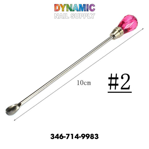 The QH3200 Nail Art Stirring Rod Tool from Dynamic Nail Supply features a stainless steel cuticle pusher with a vibrant pink, gem-like handle that measures 10 cm and includes a scooped end. It is perfect for intricate nail art in any manicure routine. The Dynamic Nail Supply brand name appears at the top, accompanied by #2 and the contact number 346-714-9983, making it an essential tool crafted for those who strive for polished perfection.