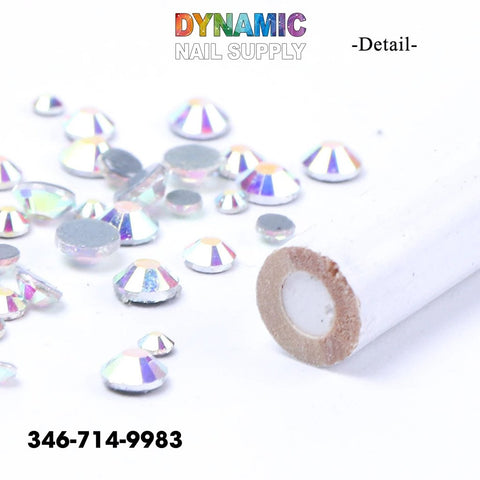 An assortment of rhinestone crystal gems glimmers on a white surface. Next to them is a cylindrical white-handled detailing brush featuring brown bristles. Above, "QHTR360 Wooden Nail Dotting Pencils for Rhinestone Crystal Gem Nail Art Decoration by Dynamic Nail Supply" is showcased, offering premium nail art decoration tools. For inquiries, call 346-714-9983.