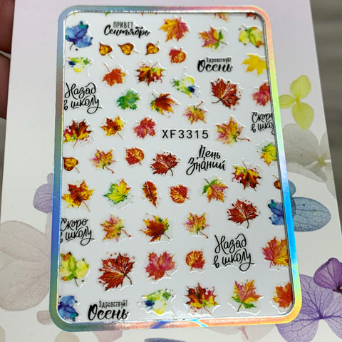 The Dynamic Nail Supply's FALL Nail Designs Stickers for Fall Season 2021 feature a vibrant collection of autumn leaves and Russian phrases such as Привет Сентябрь, Возвращение в школу, and День Знаний. This sheet comes with a white background accentuated by a holographic border, making it an ideal addition to your fall nail art. Product Code: XF3315.