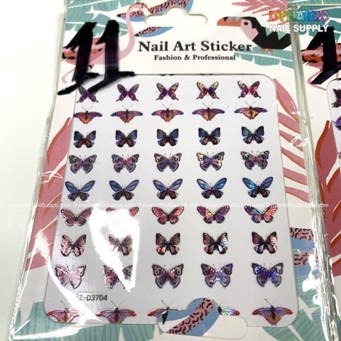 A package from Dynamic Nail Supply offers "Butterfly Stickers for Nails Art Design," showcasing colorful, iridescent butterfly designs in assorted sizes and styles. The packaging features a pastel-colored abstract pattern with pink, blue, and orange splashes, along with the text "Nail Art Sticker Fashion & Professional".