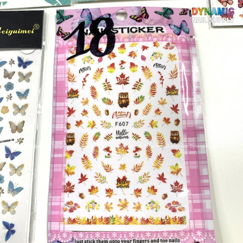 Autumn-themed sticker sheet for nails art enthusiasts, featuring owls, leaves, pumpkins, and phrases such as "Hello Autumn." The design includes a whimsical touch with butterfly stickers on the left over a pink plaid background. This product is part of Dynamic Nail Supply's collection.