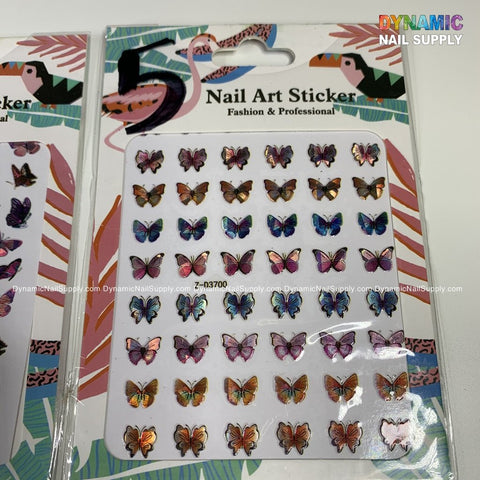 Photo of two packs of Dynamic Nail Supply's Butterfly Stickers for Nails Art Design - 5. Each pack displays rows of vibrant butterfly stickers with shimmering, metallic finishes, ideal for enhancing your nail art. The packaging has abstract patterns and text that says "Nail Art Sticker: Fashion & Professional.