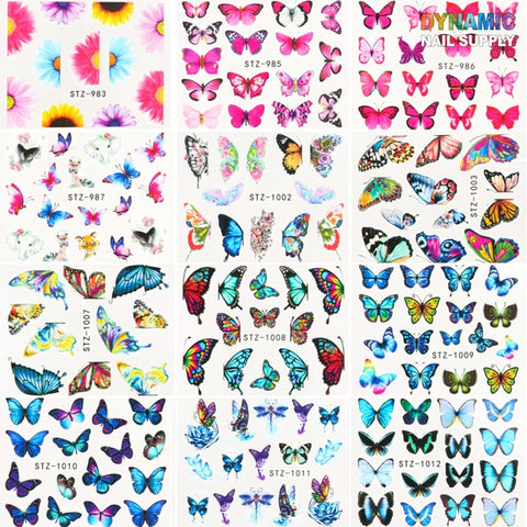 A collage of designer butterfly nail art designs, labeled with product codes STZ-983 to STZ-1013, showcases 24 sheets of vibrant butterfly patterns in pink, blue, purple, and multicolor on a white background from the Butterfly Water Decals - 3D Nail Art Decoration Decals for Designer collection. The top right corner proudly features the "Dynamic Nail Supply" logo.