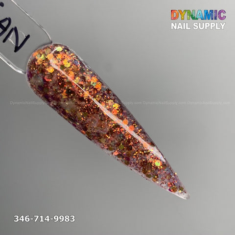 Close-up of a long, pointed nail display featuring Carnelian #330 - Acrylic Glitter Powder with a blend of orange, gold, and red sparkles against a gray background. "Dynamic Nail Supply" is prominently displayed in colorful letters at the top right, highlighting their dip essentials for durable nails. A phone number is located at the bottom left.