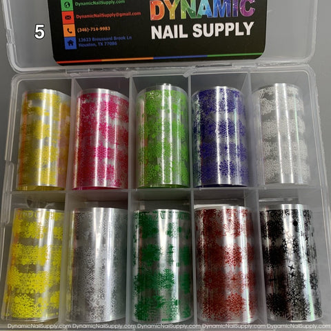 A set of ten Christmas Nail Art Foils - [05] from Dynamic Nail Supply, neatly stored in a plastic organizer. Each foil roll showcases unique floral and abstract designs in festive colors such as yellow, pink, silver, and green. Ideal for crafting creative Christmas nail art!
