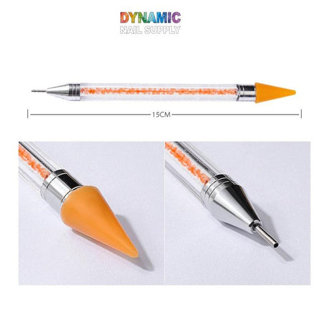 Introducing the Dual-head Rhinestone Picker Pen by Dynamic Nail Supply, a versatile tool designed for precision tasks. One end features an orange silicon tip, while the metal detailer on the other ensures accurate application. The clear handle is filled with small orange beads and measures 15 cm in length, adding vibrant style to this dotting tool that doubles as a rhinestone picker pen.