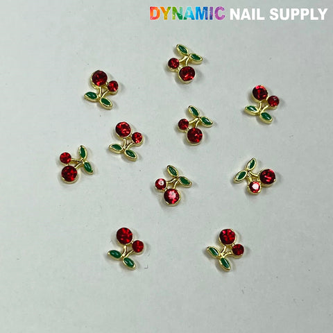 Tiny red cherry charms are scattered on a plain background, each adorned with red rhinestones and green leaf accents for dazzling nail art. The text "Dynamic Nail Supply" is prominently displayed in the top right corner. This is the 10-piece set of Small Red Cherry Charms for Nails Art Designer by Dynamic Nail Supply.