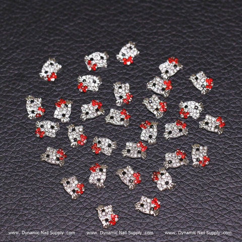 Explore an eye-catching array of 30 Metal Hello Kitty Design Nail Charms, crafted from zircon alloy. These charms showcase clear rhinestones for the face and vivid red stones for the bow. Ideal for nail accessories lovers, they are presented beautifully on a textured black background with DynamicNailSupply.com at the bottom.