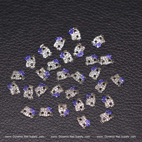 Thirty royal blue Hello Kitty nail charms (zircon alloy) are scattered on a textured black surface.