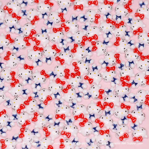 The image features a set of (Red & Blue) 100 pcs Cute Resin Hell0 Kitty Design Nail Charms by Dynamic Nail Supply, portraying small white cat-shaped decals with red bows and facial features in blue and black. These charming nail decals are scattered across a pink background, offering a whimsical and cohesive design pattern.