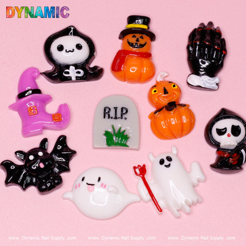 A selection of the 10 pcs Cute Cartoon Halloween Design Nail Charms from Dynamic Nail Supply, artistically displayed on a pink background. The delightful collection features whimsical designs of a ghost, pumpkin, witch hat, black cat, gravestone, skeleton hand, bat, and reaper—all bursting with vibrant colors and intricate details.