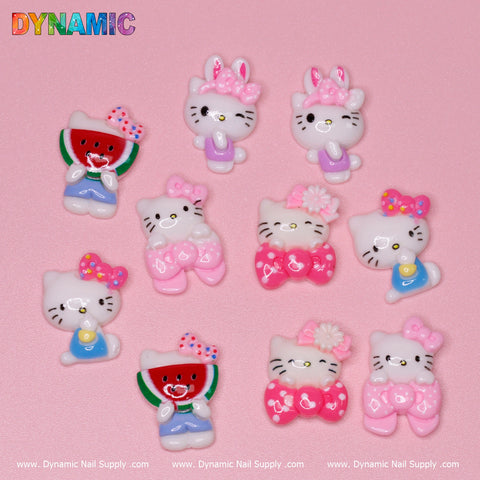 A set of 10 Very Cute Hello Kitty Cat Family Design Nail Charms, showcasing delightful Kawaii designs with watermelon motifs, floral patterns, and pink and white bows, are displayed on a pink background. The Dynamic Nail Supply brand is prominently featured at the corners.
