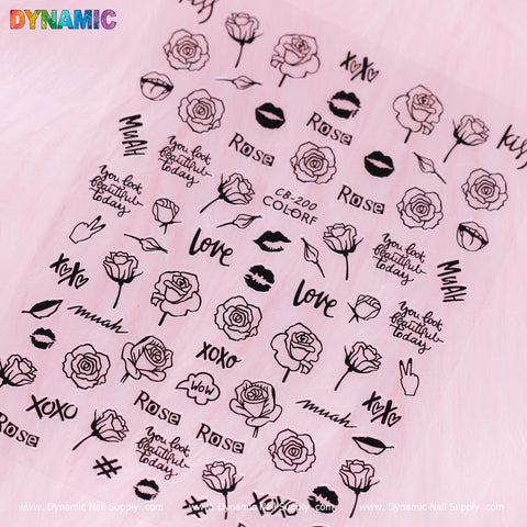 A sheet of the "hand writing art (black) (CB 200)" nail stickers from Dynamic Nail Supply is displayed on a pink background, featuring designs of roses, lips, xoxo, and muah. Charming phrases like "you look beautiful today" and "love" are complemented by the colorful text "DYNAMIC" at the top left corner. Perfect for adding a chic touch!