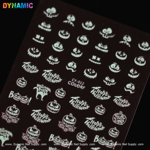 A sheet featuring white Halloween-themed nail art stickers, including glow-in-the-dark jack-o-lanterns, "Happy Halloween" text, a cat, "Trick or Treat" text, and ghosts on a black background. Each design is repeated multiple times across the sheet. The bottom of the sheet displays Dynamic Nail Supply's "Halloween glow in the dark (CY 012)" collection.