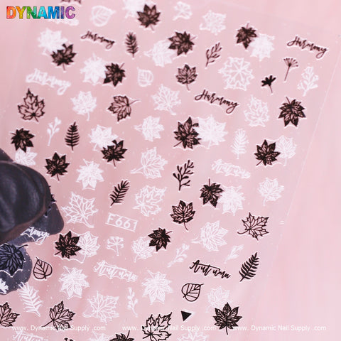 Discover the Fall Leaves nail art sticker sheet from Dynamic Nail Supply, featuring black and white fall leaf designs like maple and fern. Some stickers also include words such as Harmony and Autumn. The light pink background enhances the display, accompanied by the DYNAMIC logo in colorful letters at the top left corner. Model F 661 brings a unique touch to your style.