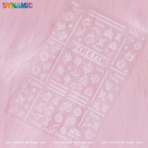 Against a pink backdrop, a transparent sheet displays white zodiac symbols and icons. The top is labeled “ZODIAC,” highlighting designs for each white zodiac sign, such as Aries, Taurus, Gemini, Cancer, Leo, Virgo, Libra, Scorpio, Sagittarius, Capricorn, Aquarius and Pisces. This product is branded by Dynamic Nail Supply and named Zodiac Sign (White) (R 087A).