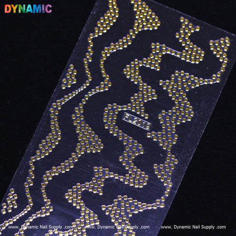 A sheet showcasing the Gold dot pattern art (FL 2019) is crafted from small gold studs arranged in zigzag lines on a black background, emphasizing the contrast. In the top left corner, the colorful Dynamic Nail Supply logo stands out, and near the center is a prominently displayed rectangular label with "LE-Series.