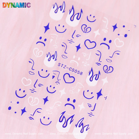 On a soft pink background, a sheet of blue and pink nail stickers showcases designs such as smiley faces, sad faces, abstract face emojis, flames, musical notes, and hearts. The center features "STZ CS058" with "Dynamic Nail Supply" stylishly handwritten along the borders.