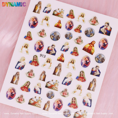 A sheet of vibrant religious-themed nail stickers from Dynamic Nail Supply, titled "Jesus and Mary" (913), showcases images of Jesus, the Virgin Mary, and other figures. Each colorful sticker encapsulates various poses and expressions against a soft pink background, with the brand name "Dynamic" elegantly printed in the top left corner.