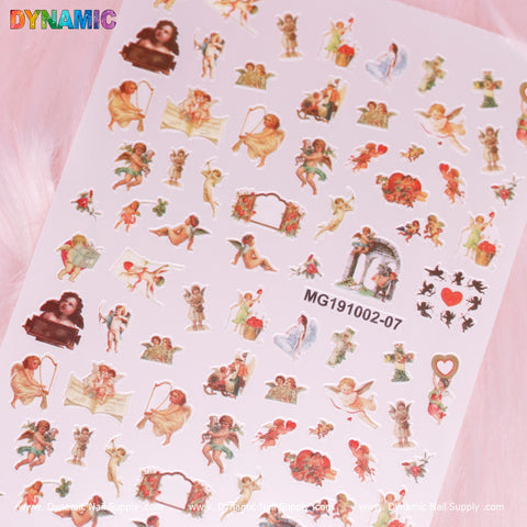 A sheet of Cupid, Angel Stickers by Dynamic Nail Supply (MG191002-07) highlights vintage-style nail stickers depicting cherubs, Cupid, angels, and romantic themes. The designs include hearts, flowers, and small vignettes of cherubs in various poses set against a soft pink background.