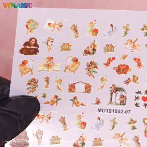 A sheet from Dynamic Nail Supply's Cupid, Angel Stickers collection (model MG191002-07) features vintage-style cherubs and cupids in delightful poses. Some play musical instruments while others sit or dance gracefully. The backdrop is white, and a gloved hand elegantly holds the sheet by the bottom corner.