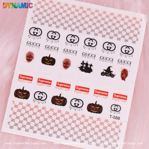 The Luxury Halloween Sticker (T-588) from Dynamic Nail Supply features a collection of logos such as Gucci and Supreme, accompanied by eerie images like pumpkins, spiders, and black cats. The top and bottom rows are adorned with refined red Gucci patterns set against a delicate pink background.