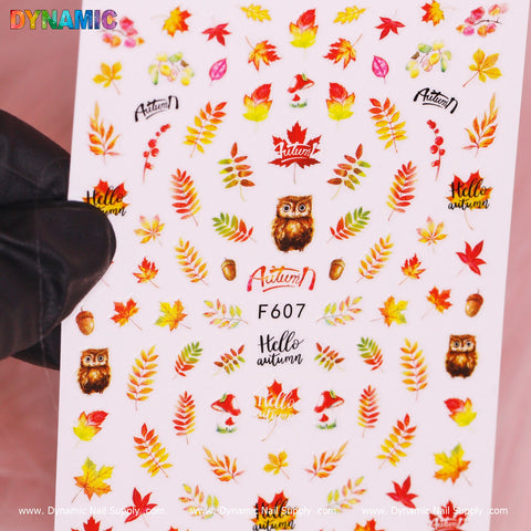 The Dynamic Nail Supply Autumn, Fall Leaves Sticker (F607) features vibrant fall leaves, acorns, owls, and mushrooms. The design is accented with the words "Hello Autumn" and "Autum," capturing the essence of fall with shades of red, orange, yellow, and green.