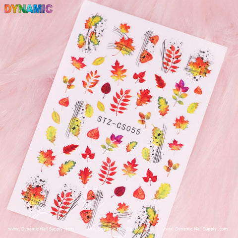 The Autumn, Fall Leaves Sticker (STZ-CS055) by Dynamic Nail Supply displays vivid autumn-themed designs, including fall leaves, red mushrooms, pumpkins, and small berries. These elements are beautifully set against a soft pink background with the product code STZ-CS055 elegantly printed in the center, capturing a charming seasonal vibe.