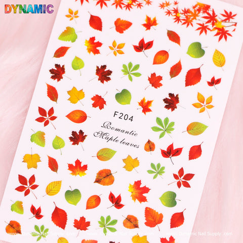 A sheet of autumn-themed stickers, titled "Autumn, Fall Leaves Sticker (F204)," features vibrant fall colors such as red, orange, yellow, and green. At its center is the text "F204 Romantic Maple Leaves," with elegantly scattered leaves on a white background and the brand name "Dynamic Nail Supply" displayed at the top left.
