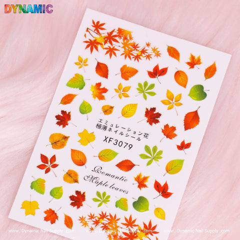 The Autumn, Fall Leaves Sticker (XF3079) from Dynamic Nail Supply features a vibrant array of romantic maple leaves in red, orange, yellow, and green. Against a light pink background adorned with the DYNAMIC logo, this sheet is perfect for embracing the autumn season.