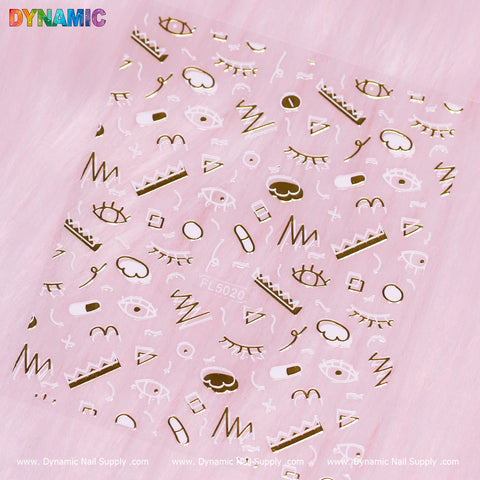 The Hand-drawing Sticker (FL5020) by Dynamic Nail Supply showcases intricate designs such as eyes, lips, squiggly lines, triangles, and circles in gold set against a transparent background. This sheet is displayed on a soft pink surface with the Dynamic Nail Supply logo prominently featured at the bottom.