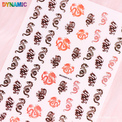 A sheet of Dynamic Nail Supply's New Chinese Dragon Stickers showcases elaborate dragon motifs in orange, black, and red tones. These dragons come in different sizes and orientations, tightly packed against a white background. In the top left corner, the word DYNAMIC is prominently displayed in colorful letters next to the product code MG200814-31.