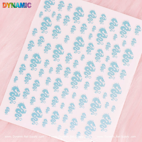 A sheet of New Chinese Dragon Sticker (T-286) on a light pink background features small, turquoise dragons in various poses. The stickers are neatly arranged in rows, and the brand name Dynamic Nail Supply is prominently displayed in colorful text in the top-left corner.