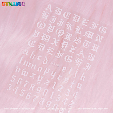 White alphabet and number decals are skillfully arranged on a pink furry background, featuring Gothic-style uppercase letters next to simpler lowercase script and numbers 0 through 9. This design evokes the Roman Letter and Number Sticker (XF3359) from Dynamic Nail Supply, with "Dynamic" prominently displayed in the top left corner.