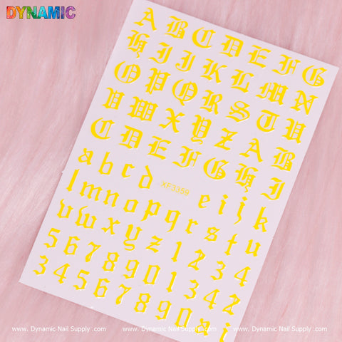 The Roman Letter and Number Sticker (XF3359) - Yellow from Dynamic Nail Supply presents yellow alphabet letters in an old English style, showcasing uppercase and lowercase letters from A to Z, as well as numbers 0 to 9 on a pink furry background. The sheet is part of the Roman letter stickers collection, with the brand name, Dynamic Nail Supply, printed repeatedly at the bottom.