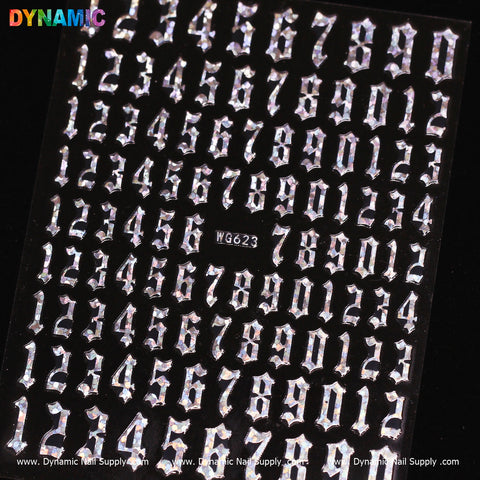 A detailed image showcases a black sheet displaying metallic, jagged-style numbers that resemble silver stickers arranged in rows from 0 to 9. The brand name "Dynamic Nail Supply" appears in vibrant letters at the top left corner, with the product code WG623 subtly visible in the center.
