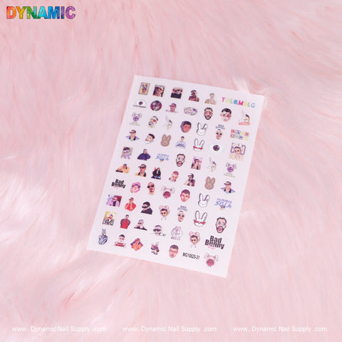 A sheet of hip hop nail stickers from Dynamic Nail Supply, showcasing the special edition Bad Bunny design along with cartoon faces, animals, and abstract shapes, is beautifully displayed on a soft pink, fluffy background. The Dynamic Nail Supply logo and website information embellish the bottom edge.